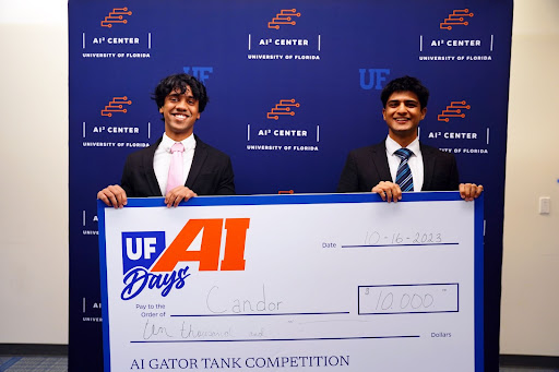 Two students in business suits holding a large check for winning UF Gator Tank competition